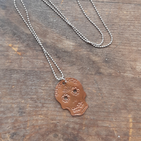 matt copper sugar skull necklace on wooden background