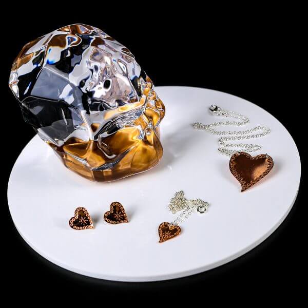 copper milagros heart collection on white plate with crystal skull