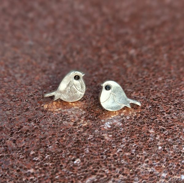 Silver robin earrings on a rose gold glitter background