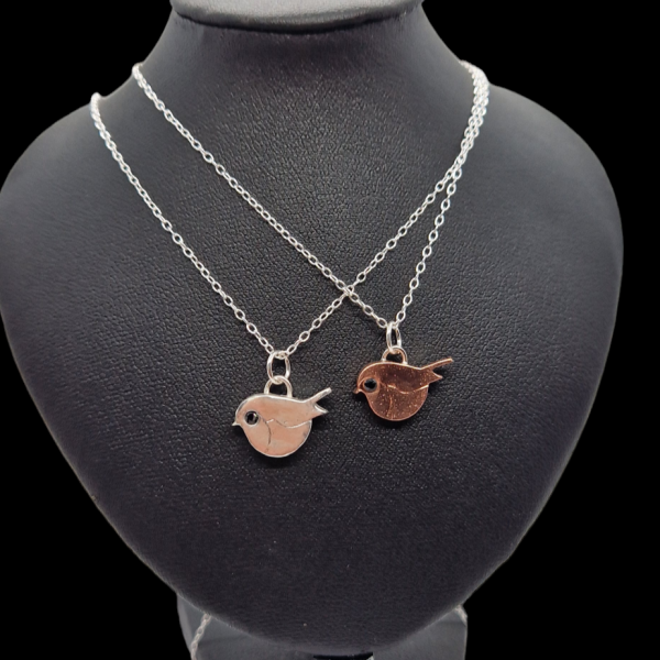 silver and copper small robin necklace with black stone for eye on silver chain on a necklace display