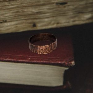 hammered chunky copper ring laying on a burgundy red book
