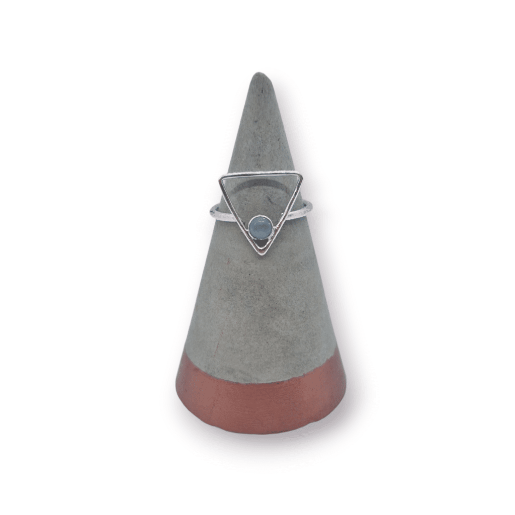 silver triangular ring with aquamarine gemstone on a grey cone on a grey background