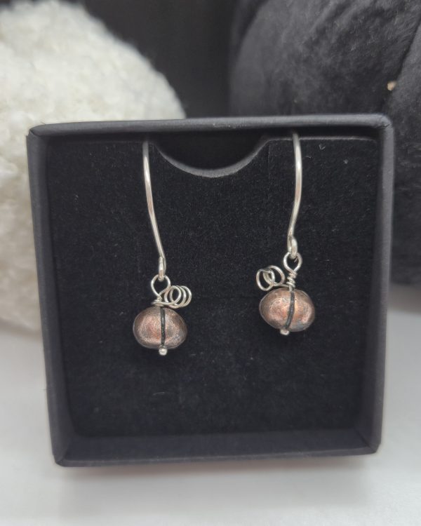 dark copper pumpkins on silver earring wires displayed in jewellery box with display pumpkins behind them