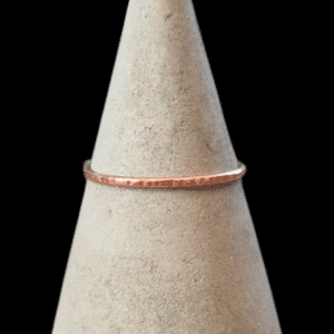 thin textured copper ring on concrete ring cone with black background
