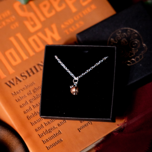 Copper pumpkin necklace in a black jewellery box on a yellow book