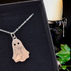 silver ghost necklace in black jewellery box with candle and ivy in background