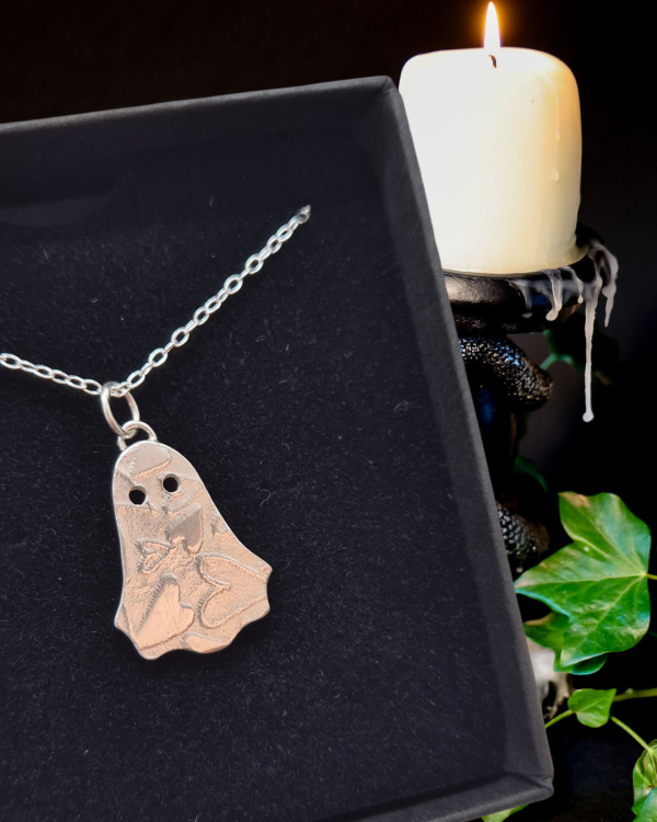 silver ghost necklace in black jewellery box with candle and ivy in background