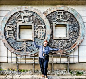 Woman stood in front of too massive copper Yen coins at Ashio Copper Mine