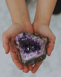 two hands holding a purple amethyst geode stone