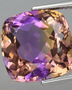 purple and yellow banded facetted crystal held with tweezers