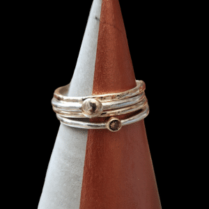 stack of gold handmade rings with brown stone set on a concrete ring cone
