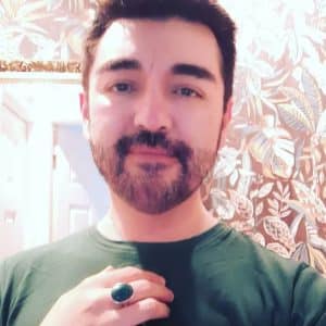 man smiling at camera holding up hand with green malachite silver ring