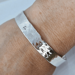 hammered textured high shine sterling silver band around a woman's wrist
