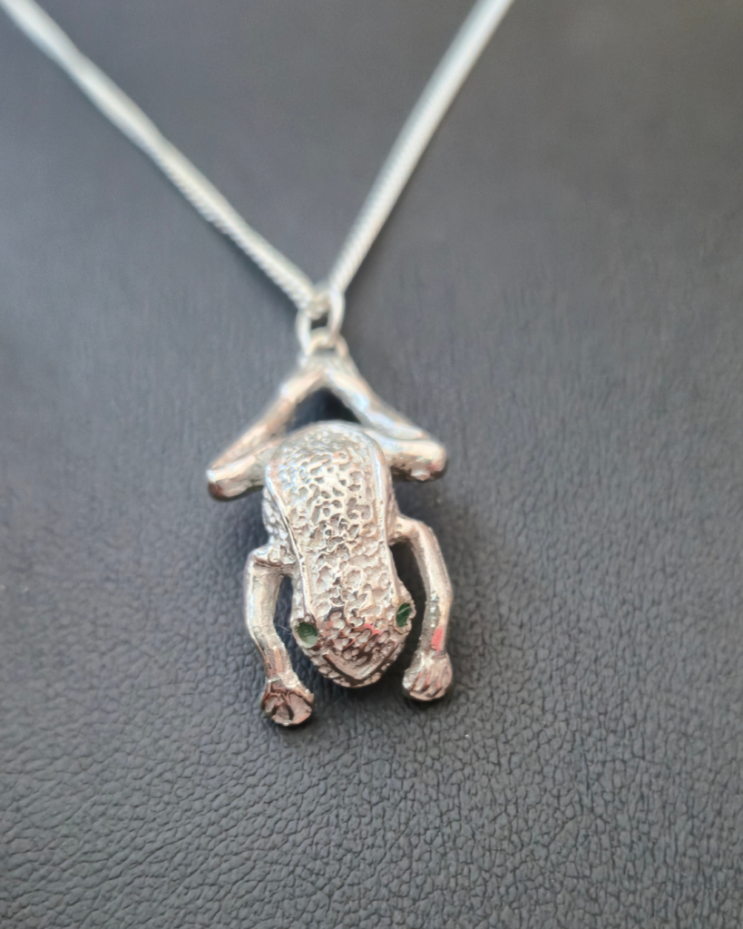 Silver frog shaped pendant with tiny emerald eyes