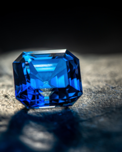a blue sapphire facetted gemstone on a dark background