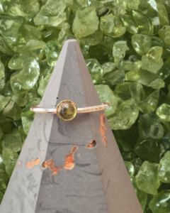 a green stone set silver ring on a grey ring cone set against a green gem background