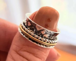 silver spinner ring with beaded and brass bands on a thumb