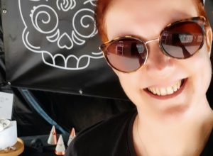 smiling woman in sun glasses in front of a market stall